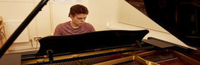 Student playing the piano in one of the music rooms. 